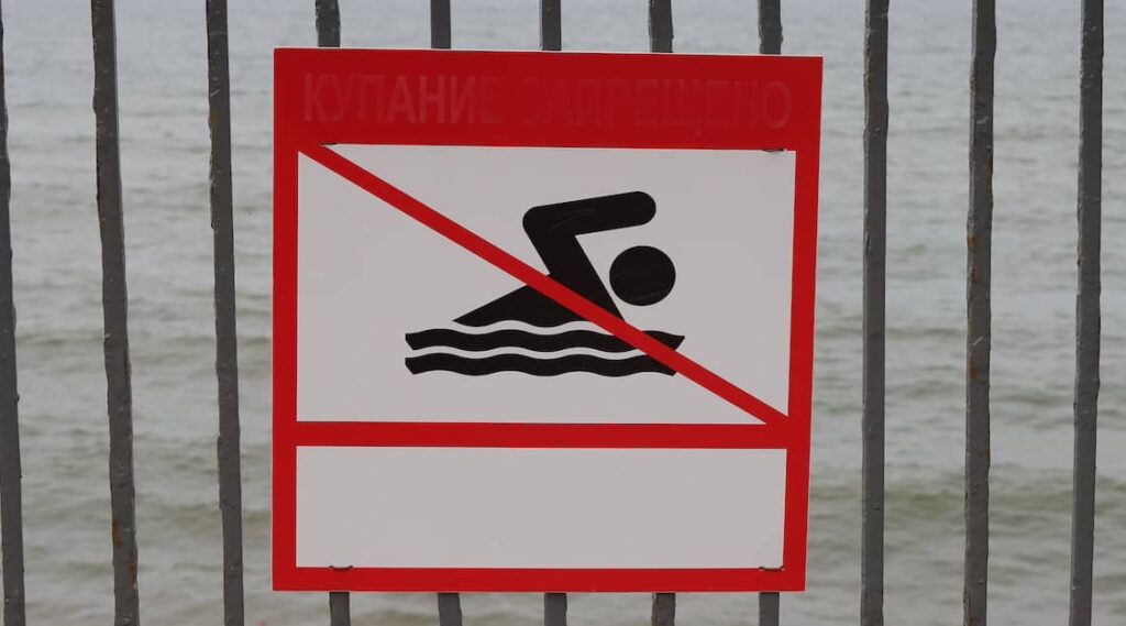 Sign warning people not to swim around a public body of water | Henry Carus + Associates