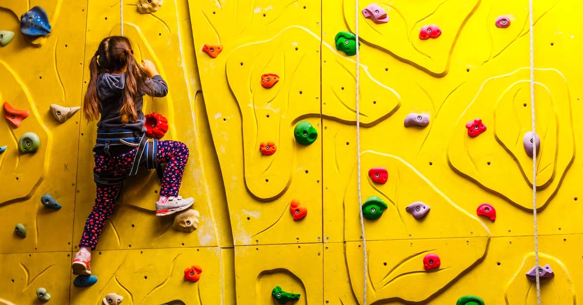 Young girl on climbing wall at indoor play centre | Henry Carus + Associates