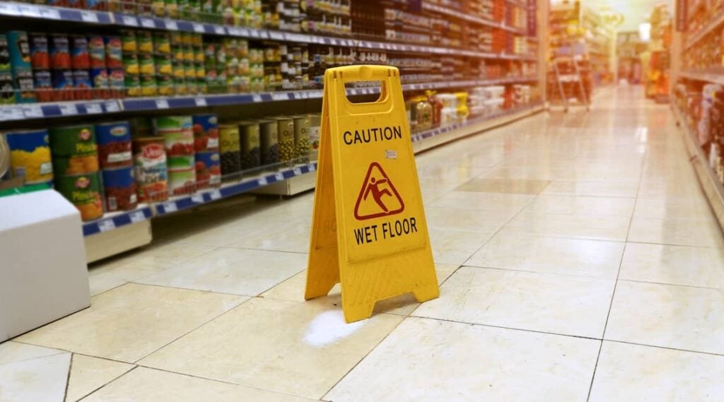 Caution: Wet Floor sign in the aisle of a supermarket | Henry Carus + Associates