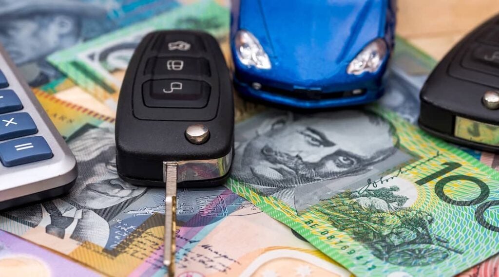 Car keys, calculator and toy car resting on Australian money | Henry Carus + Associates